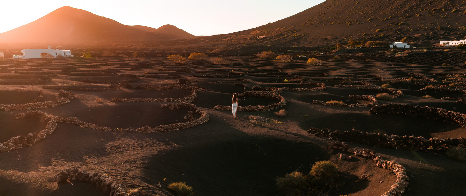 Mujer paseando al atardecer entre los viñedos volcánicos de La Geria, en Lanzarote